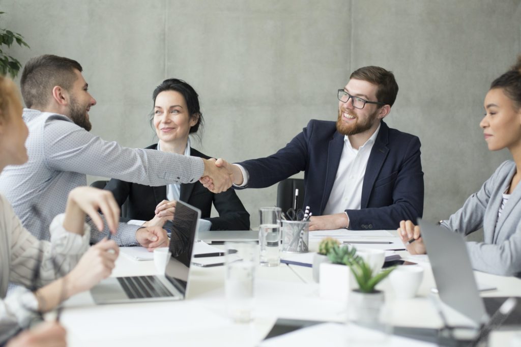 Boss shaking hands with employee at meeting