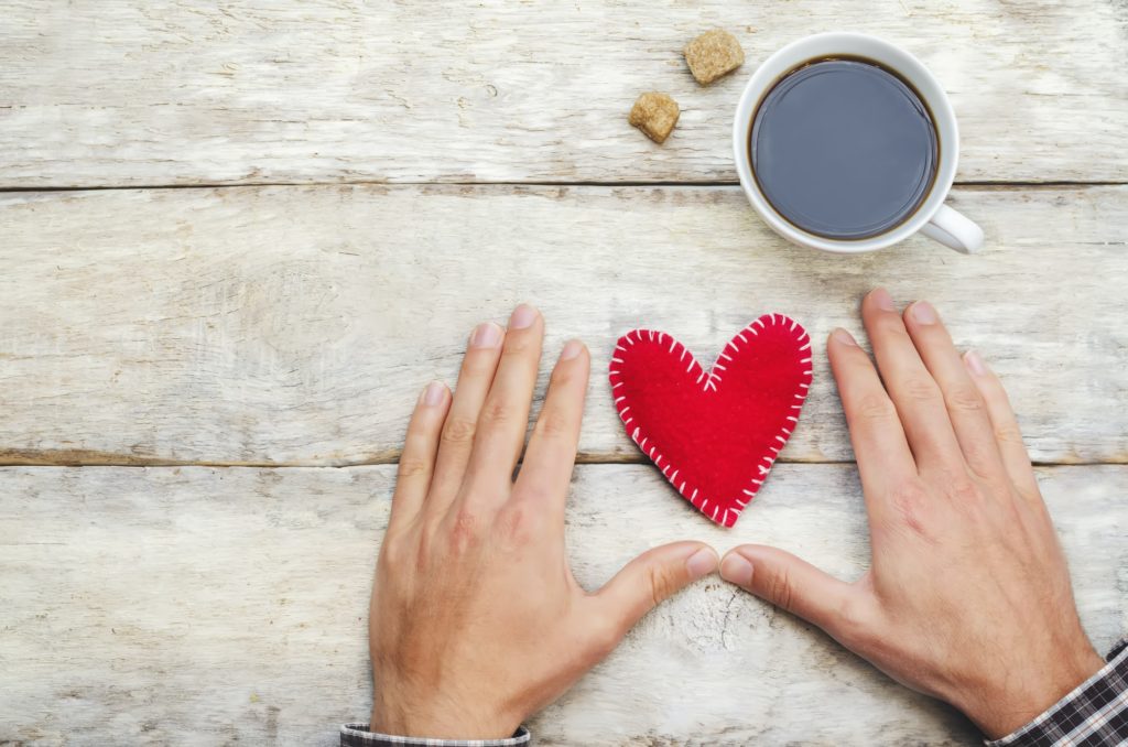 Male hands with heart and a cup of coffee